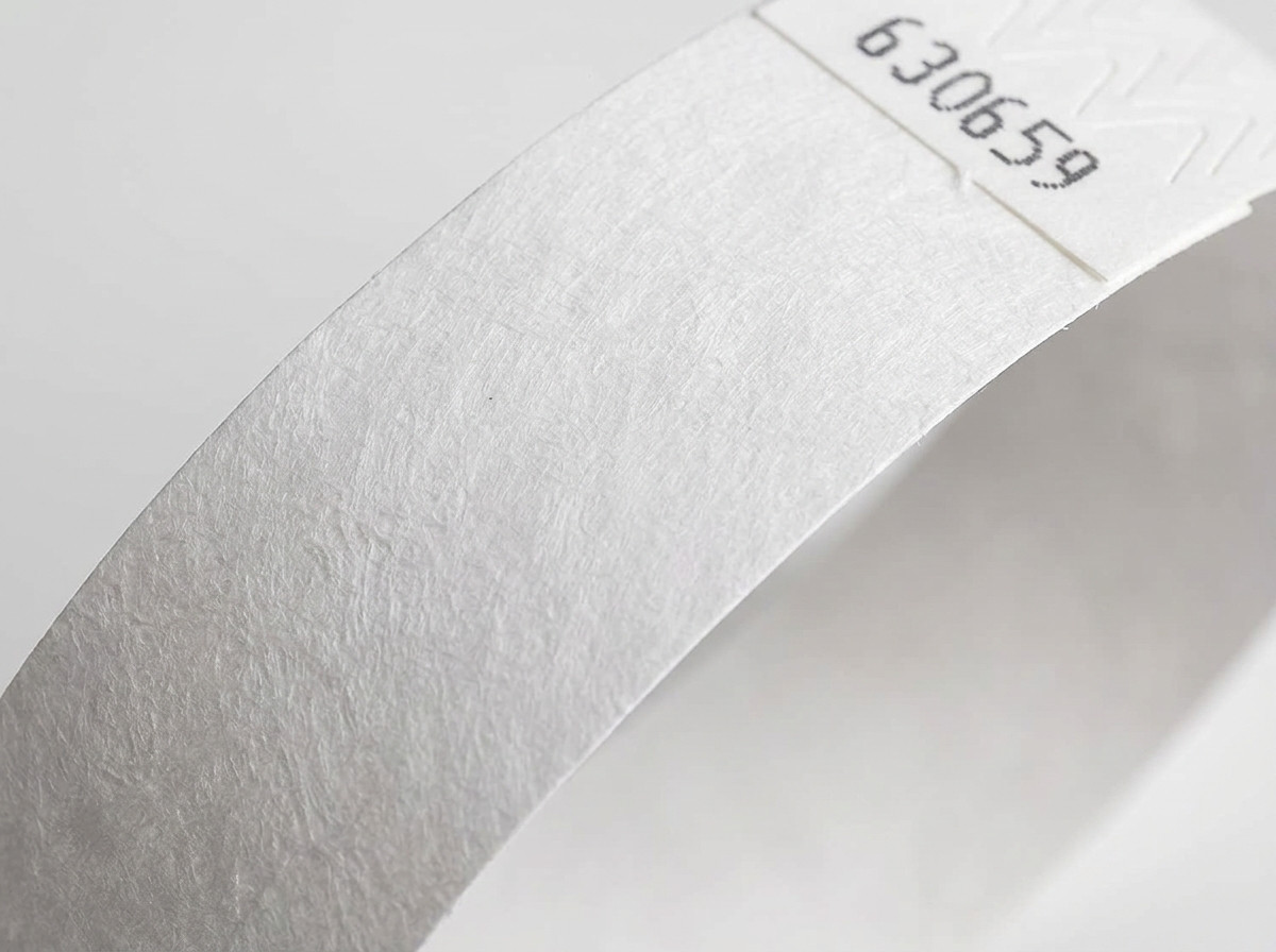 Primo piano sulla superficie non tessuta di un braccialetto Tyvek bianco, che mostra la texture caratteristica del polietilene ad alta densita